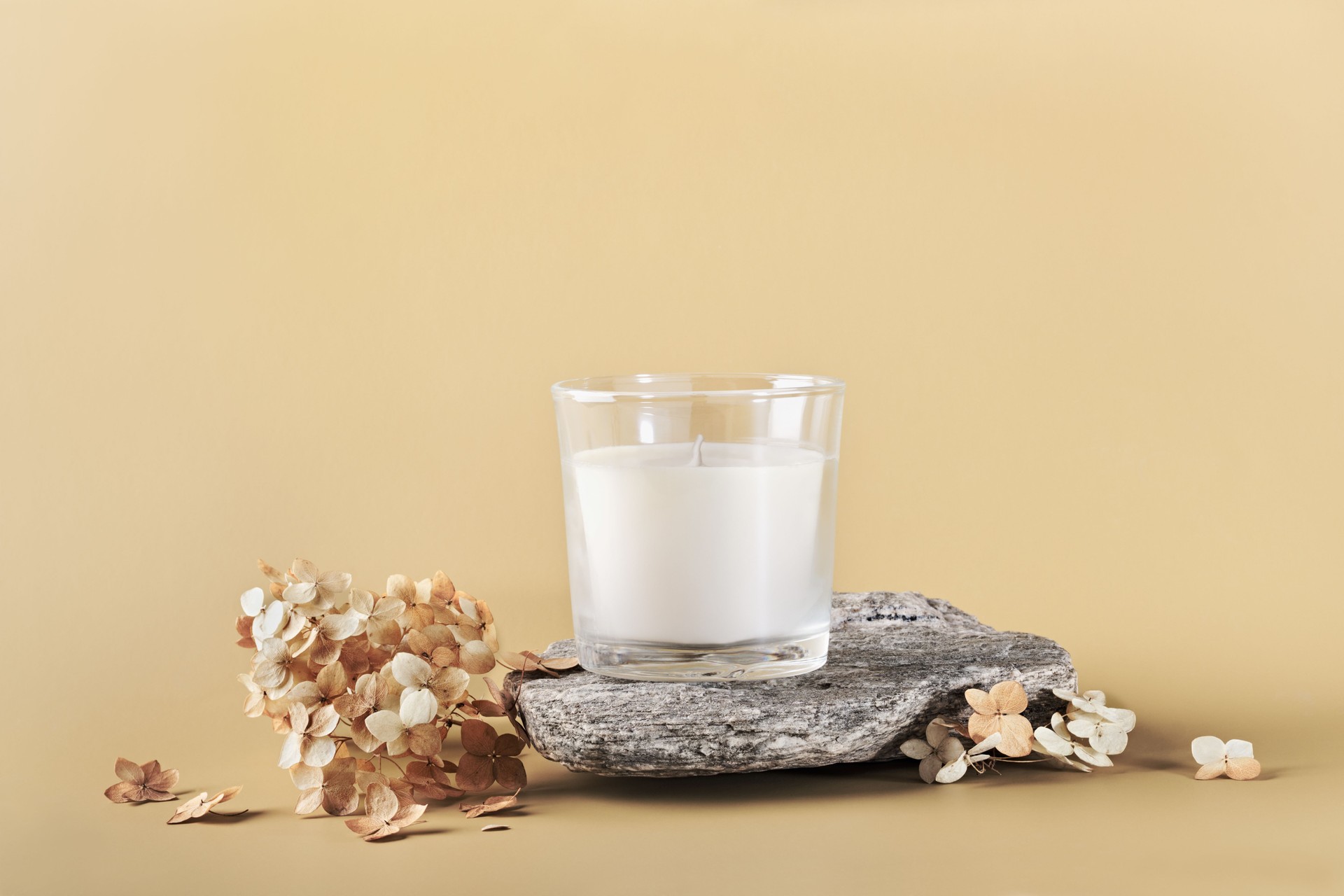 Natural candle in glass jar for branding mockup on stone podium and dried flowers. Eco friendly product packaging concept